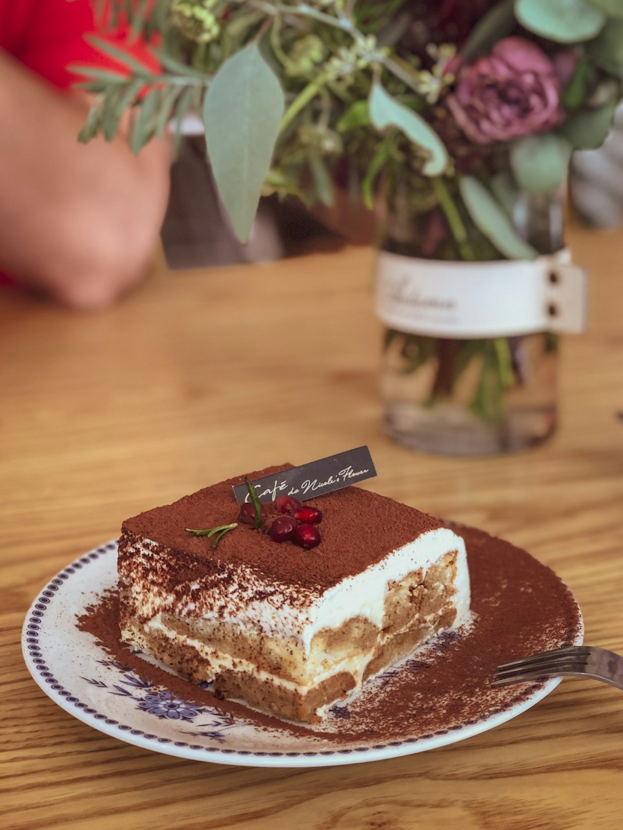 A slice of tiramisu on a plate, dusted with cocoa