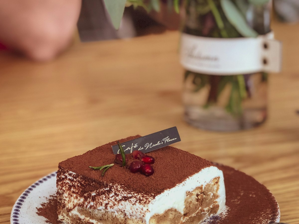 A slice of tiramisu on a plate, dusted with cocoa