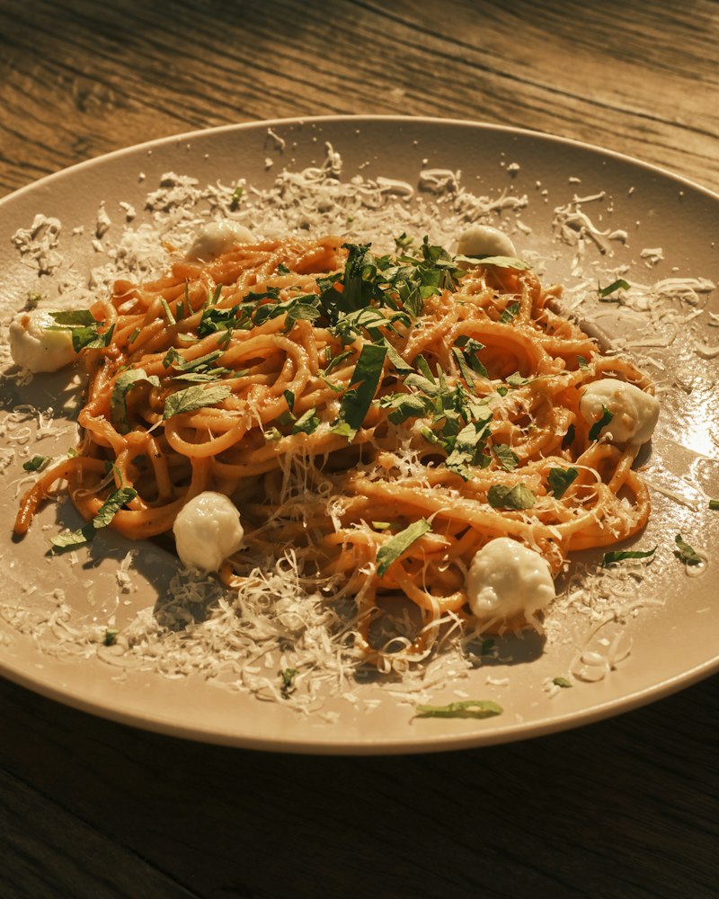 A plate of spaghetti finished with fresh cheese