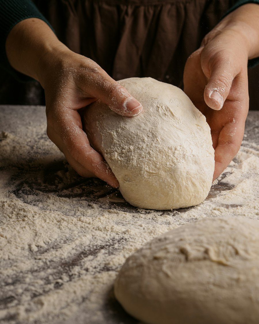 Hands kneading a ball of dough on a floured table