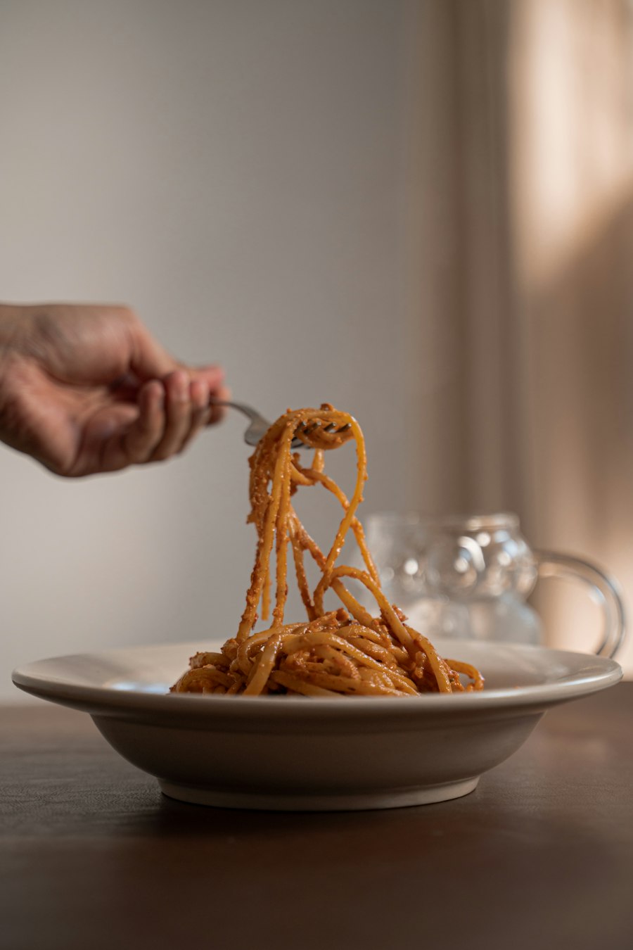 A forkful of spaghetti being lifted from a plate