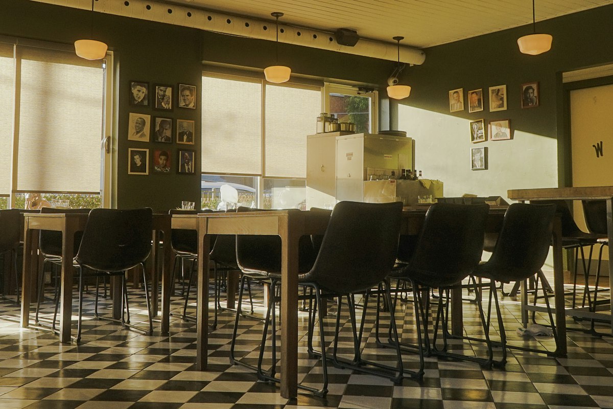 Tables and chairs in a dining room lit by warm, golden evening light