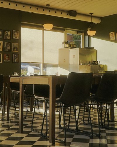 A dining room with tables set in warm, golden evening light